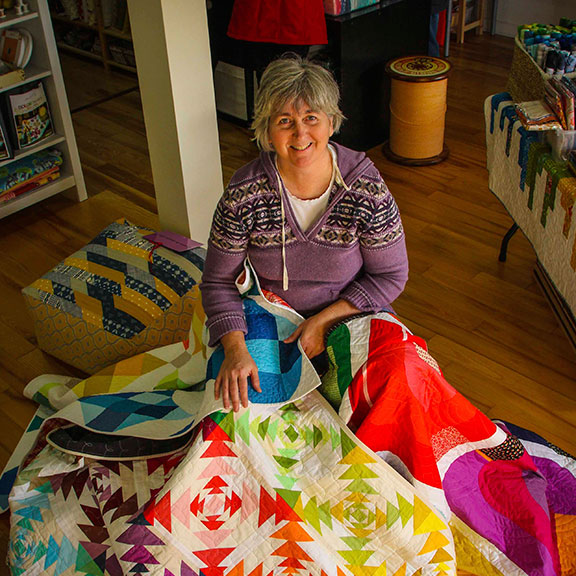Pam Denesyk with some award winning quilts in her Mad About Patchwork store. (Photo by Barry Gray)
