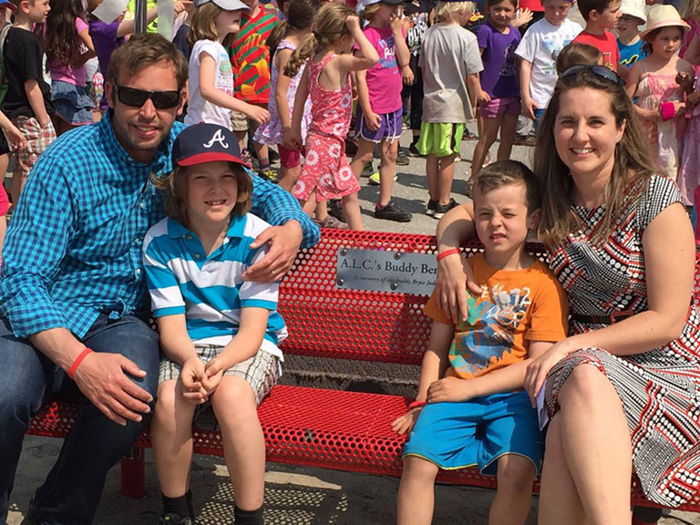 The Jude family, left to right: Steve, Mason (8), Colby (6) and Dev. They're sitting on a Buddy Bench at A. Lorne Cassidy elementary school named in memory of Bryce Jude, who passed away in 2012 after a battle with leukemia. Photo via A. Lorne Cassidy School.