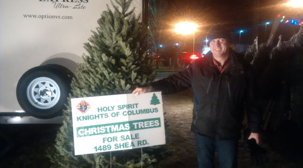 Knights of Columbus volunteer David Hatch, with one of the 8-foot balsam firs for sale.