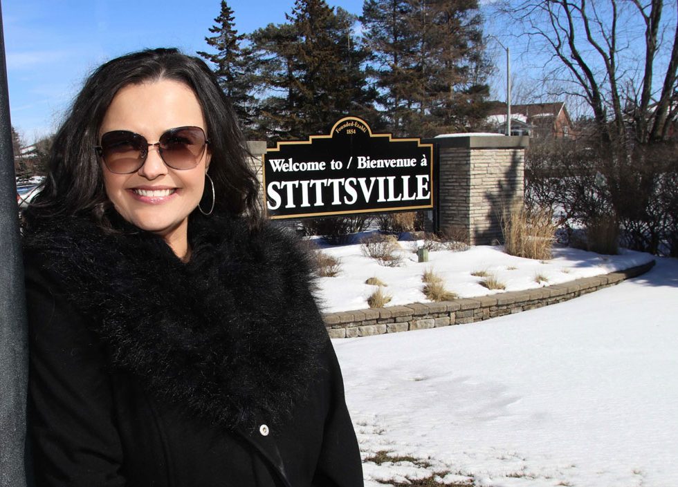 Sandra Plagakis, morning host on KiSS 105.3 in Ottawa, stands in front of the Stittsville sign